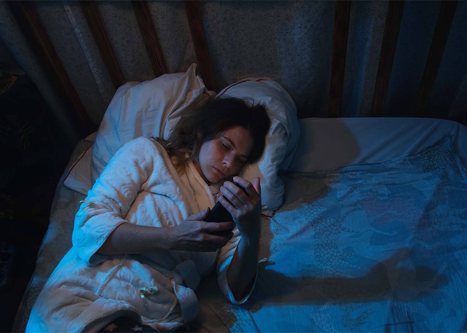 Vrouw zit op haar telefoon omdat ze niet kan slapen
